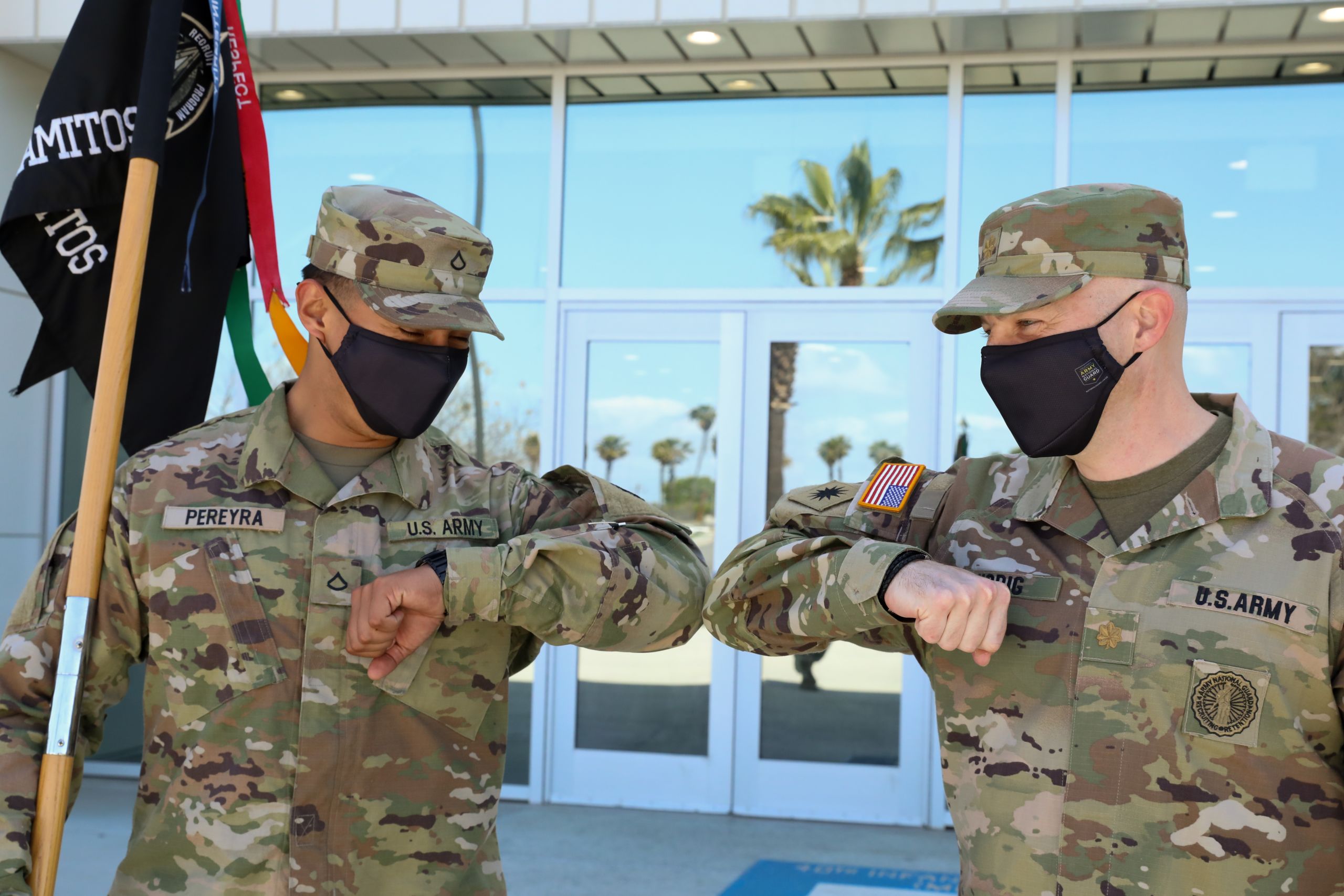 U.S. Army Pfc. Enrique Pereyra, an automated logistical specialist with the California National Guard's 40th Infantry Division shares a friendly elbow bump with U.S. Army Maj. Timothy Wobig, deputy commander with the Cal Guard's Recruiting & Retention Battalion Regional Command Post South at Joint Forces Training Base, Los Alamitos, California, March 20, 2021. (U.S. Army National Guard photo by Spc. Simone Lara)