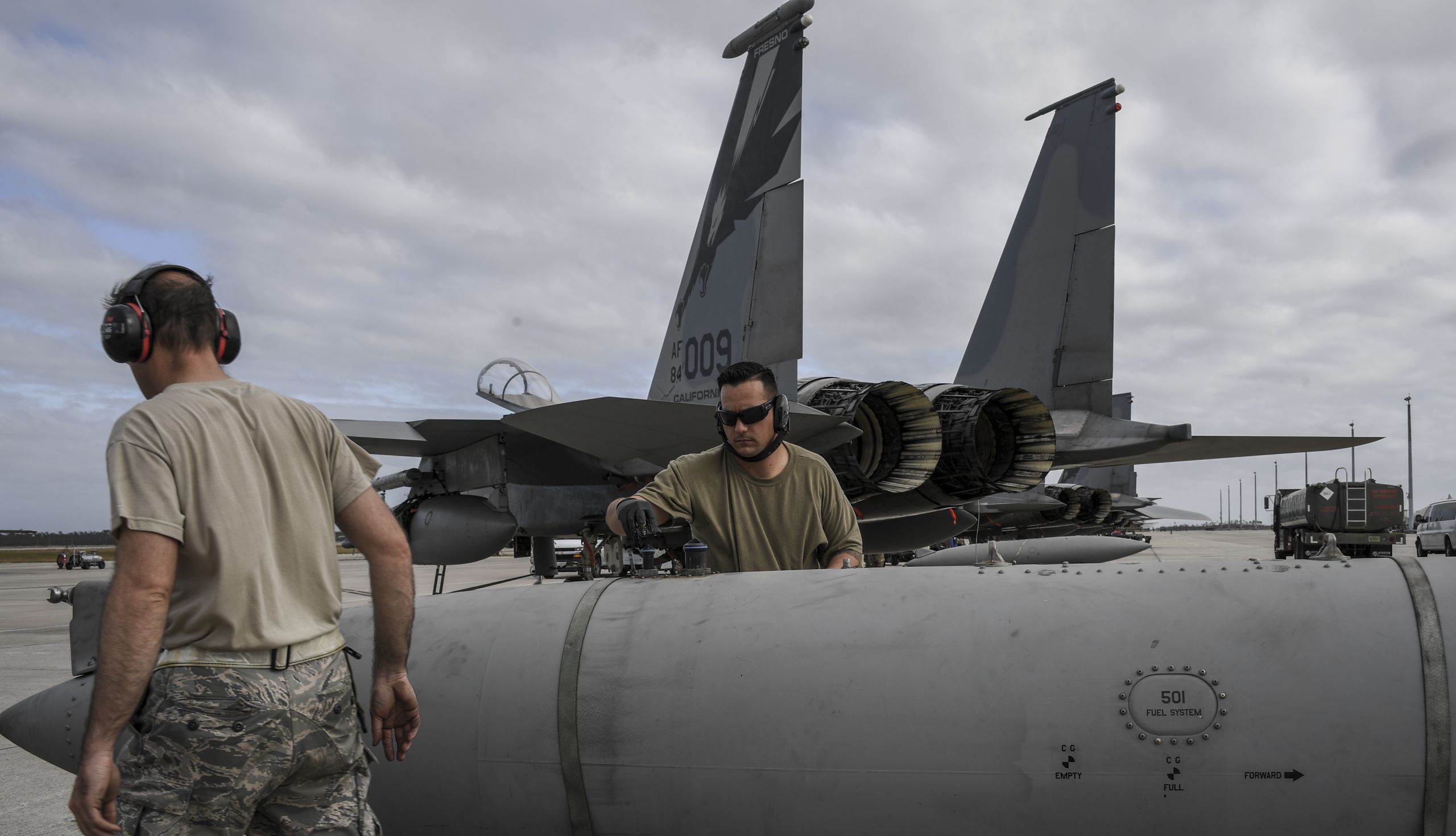 Airmen prepare an external fuel tank for a jet