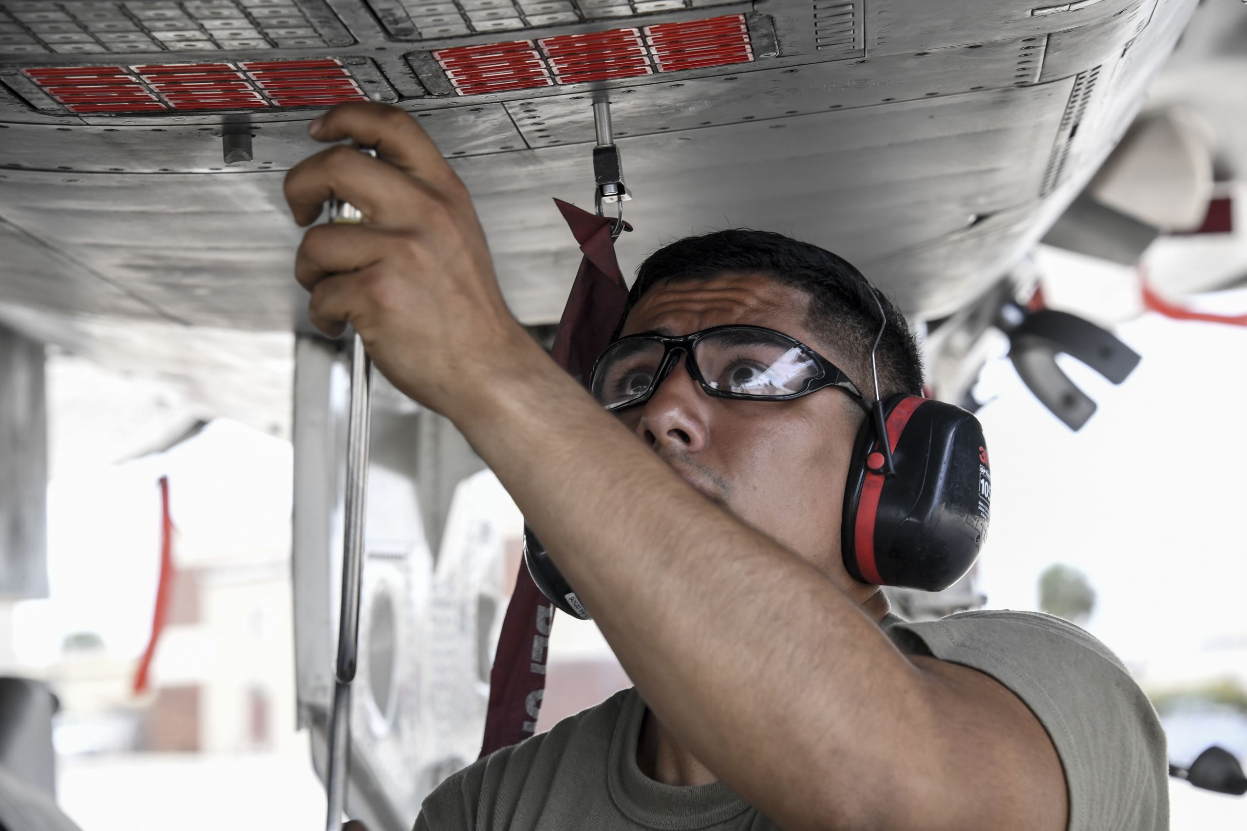 An airman inspects the bottom of a jet