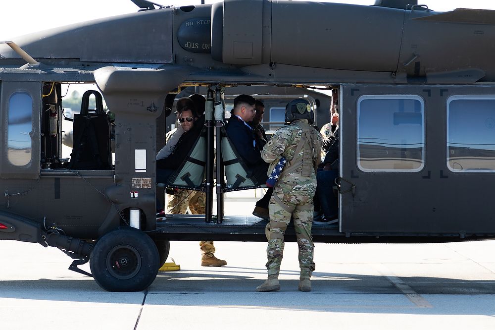 Crew chief secures passengers in helicopter.