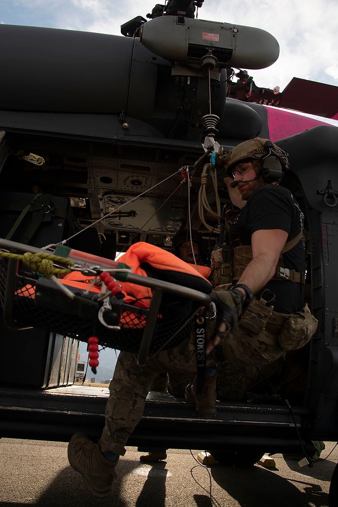 Man with litter inside helicopter.