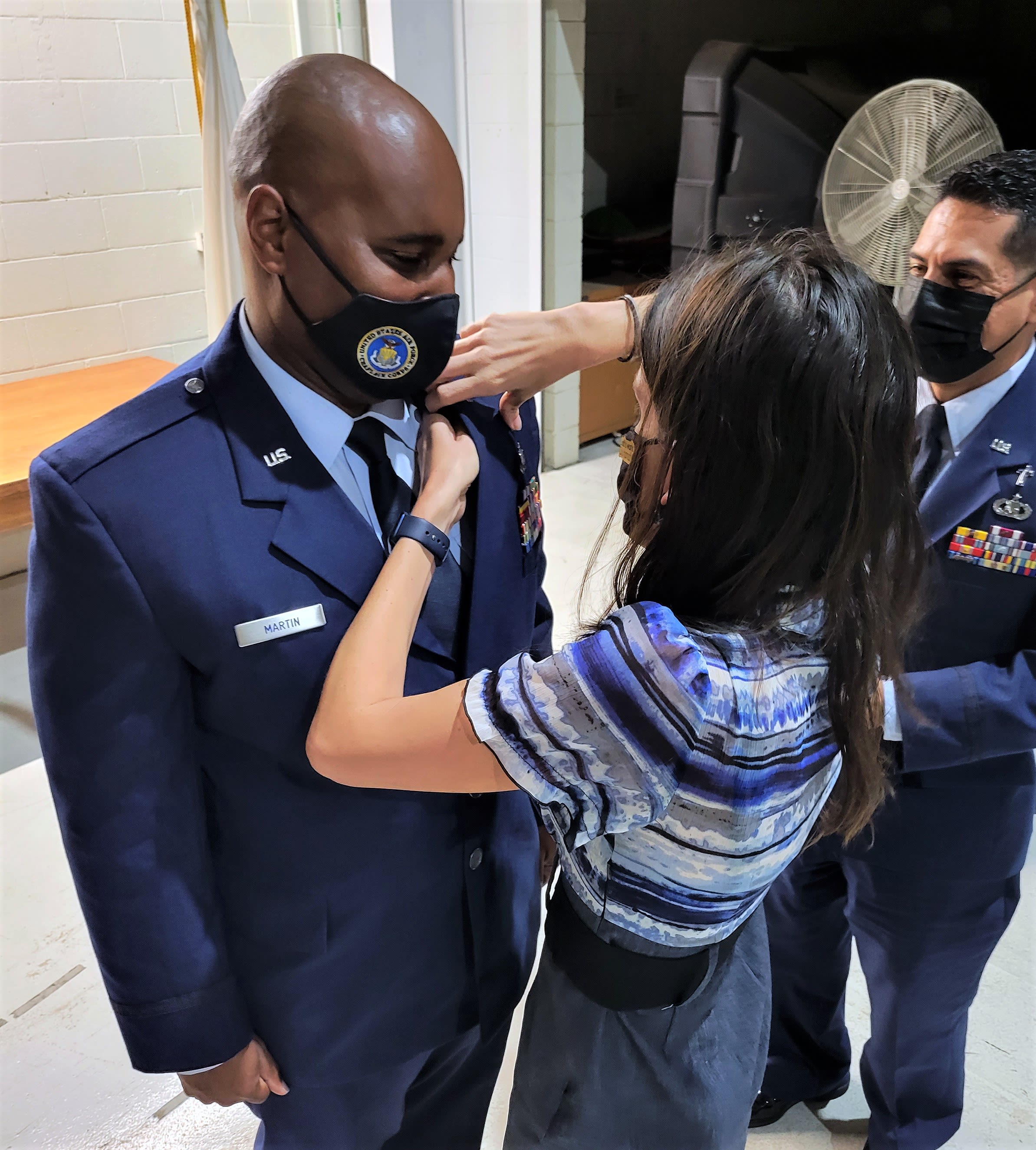 Woman pins cross on man's uniform.