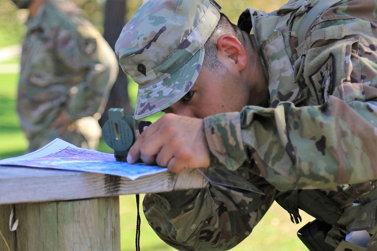 Soldier uses a compass to read a map.