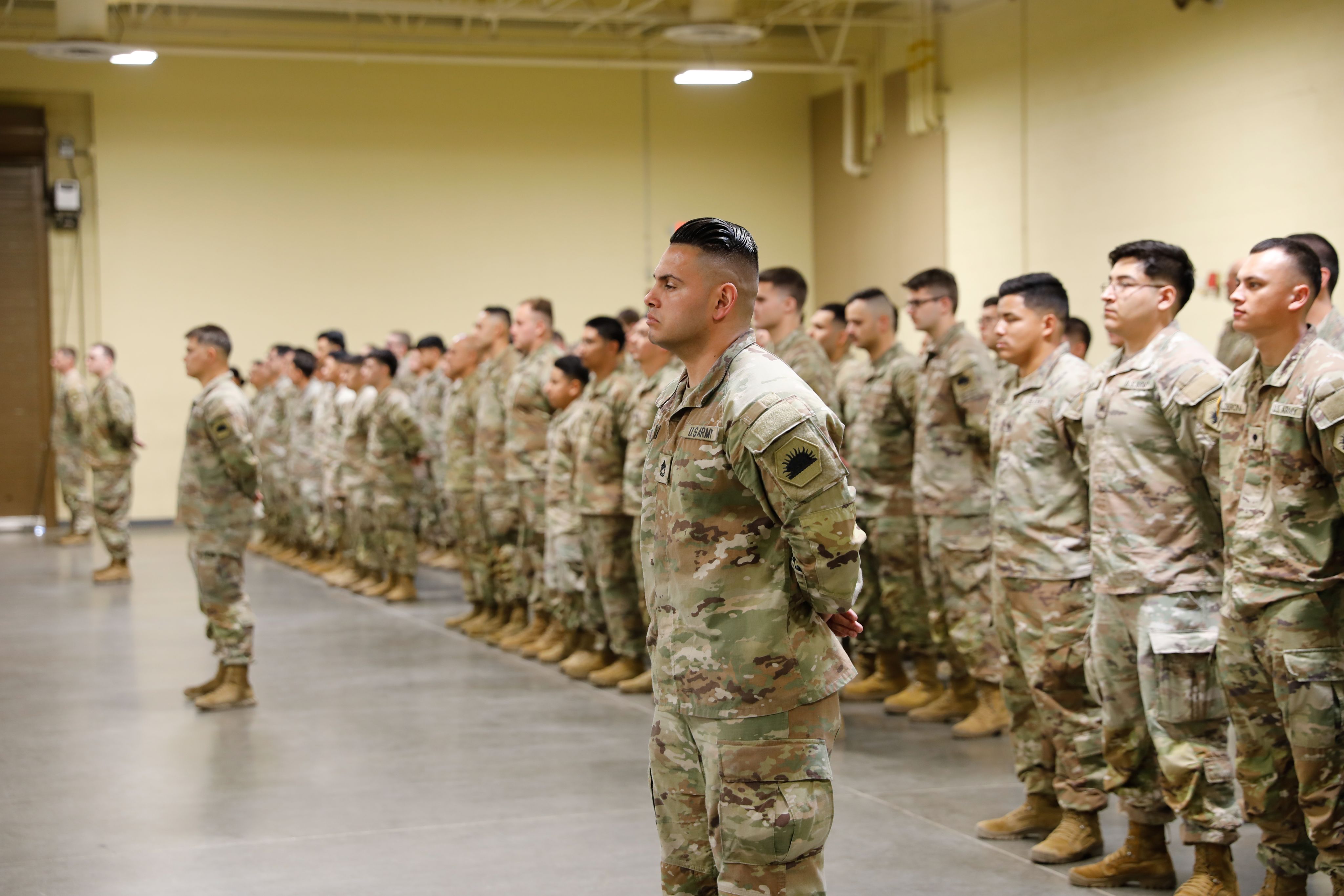 Soldiers stand in formation in a drill hall