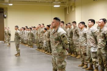 Soldiers stand in formation in a drill hall