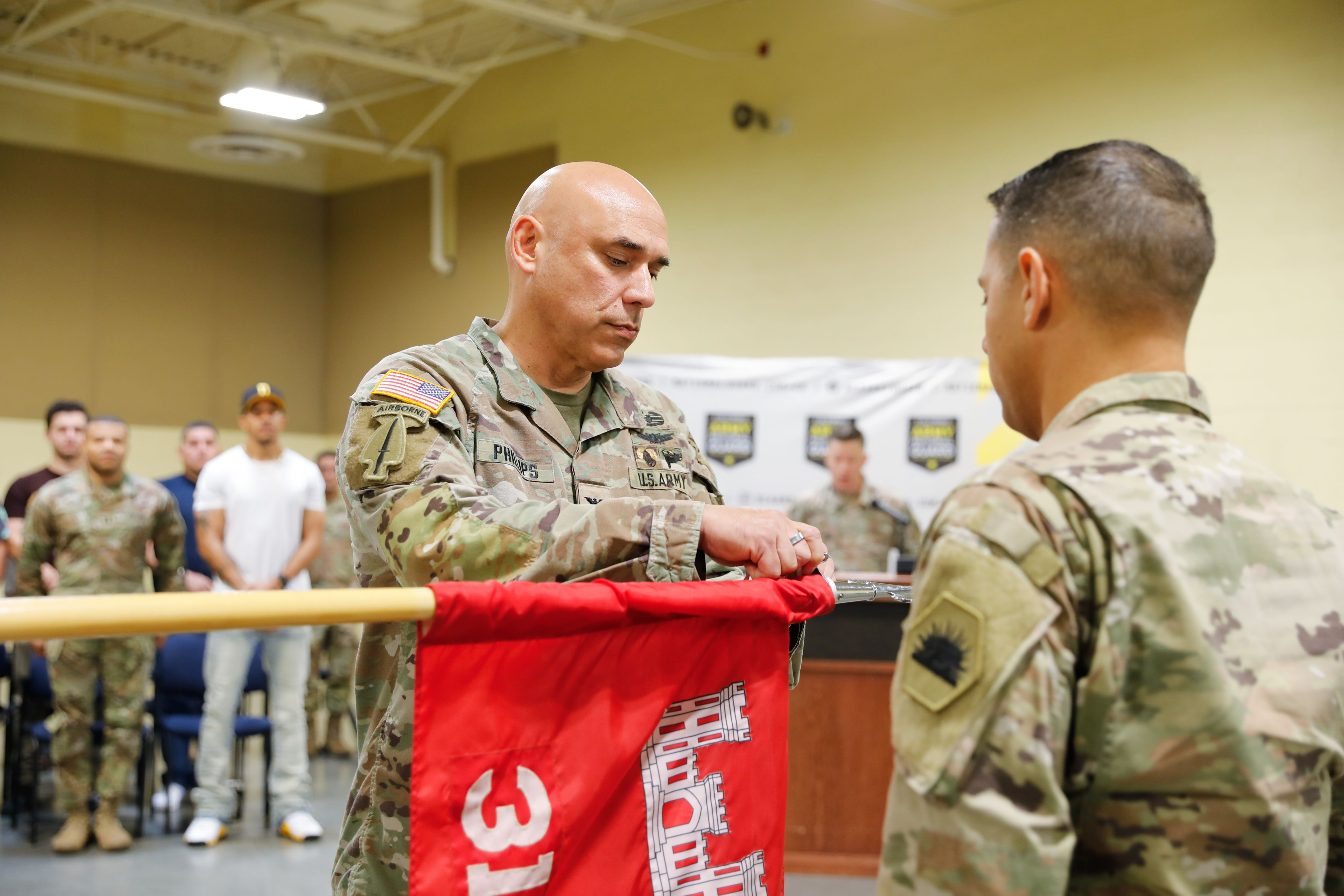 A Soldier attaches a ribbon to a unit flag