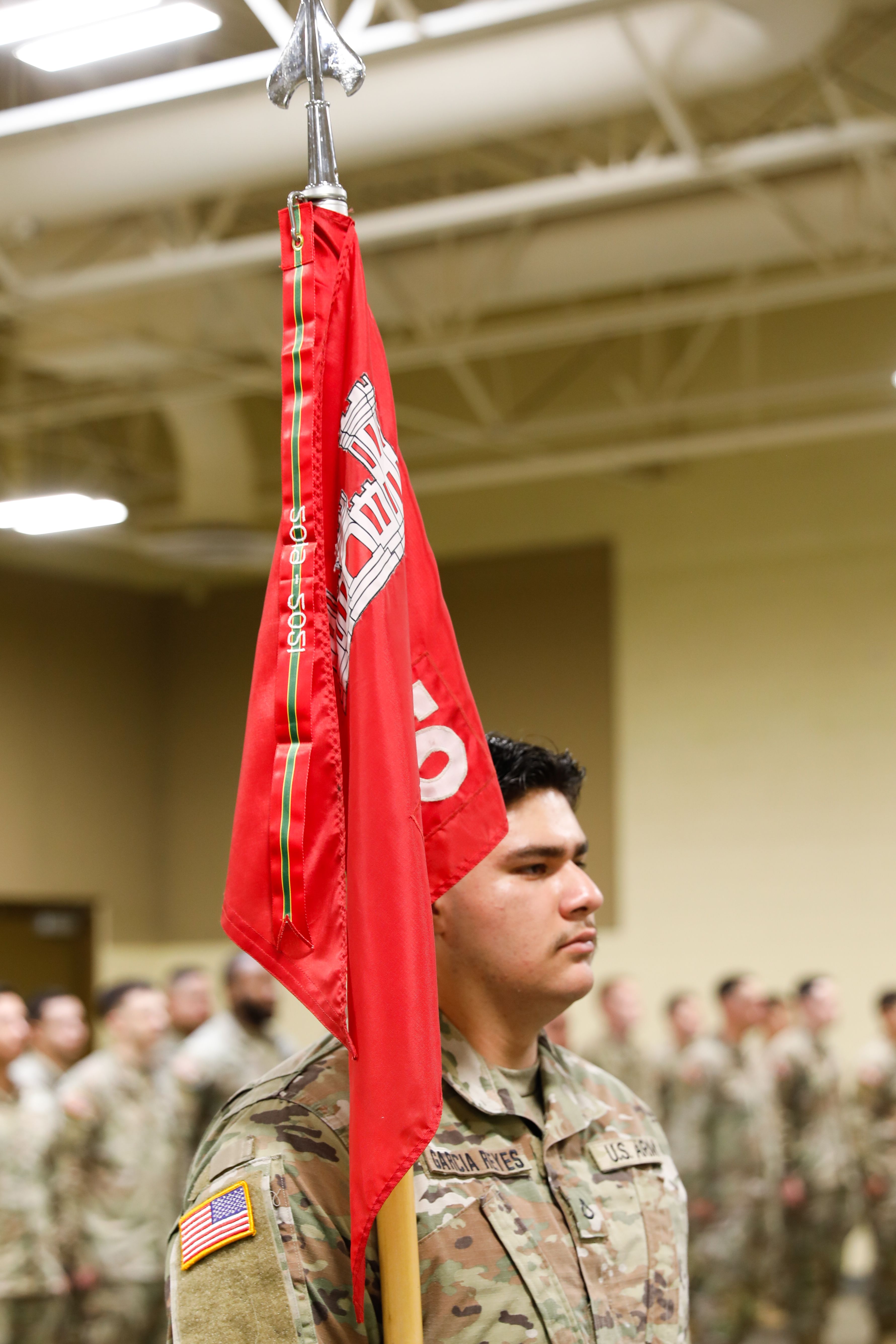 A Soldier holds a red unit flag during an award ceremony