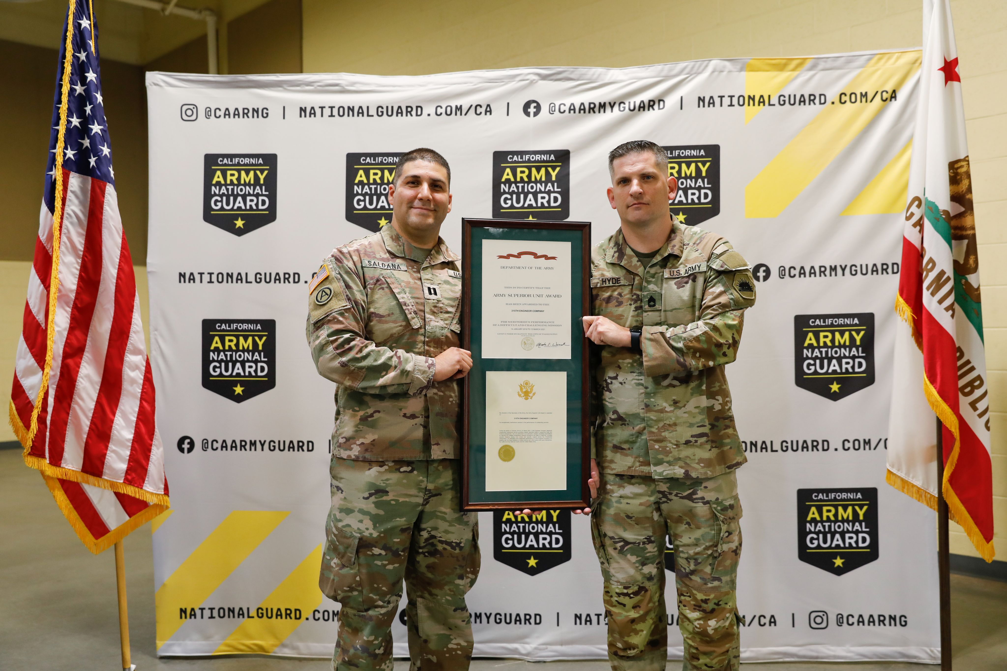 Two Soldiers hold up an award plaque