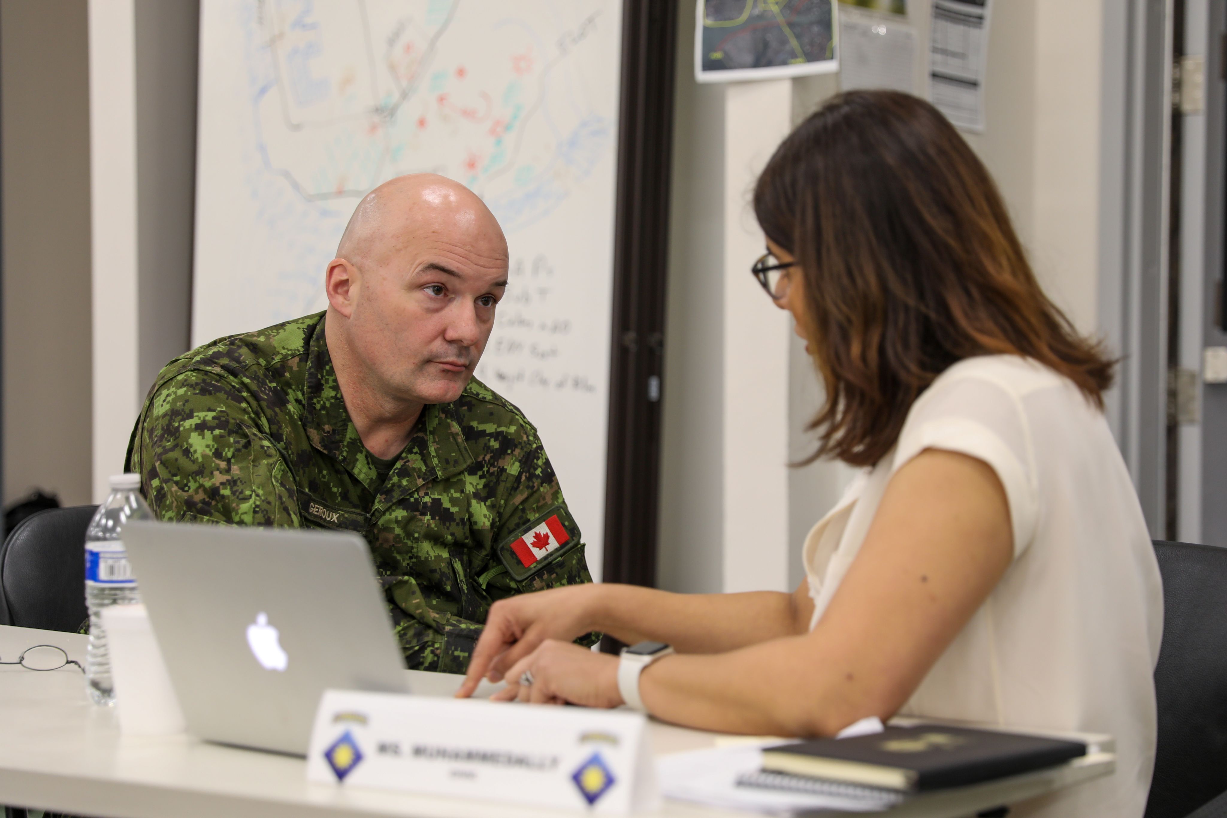 Man in military uniform talks to woman.