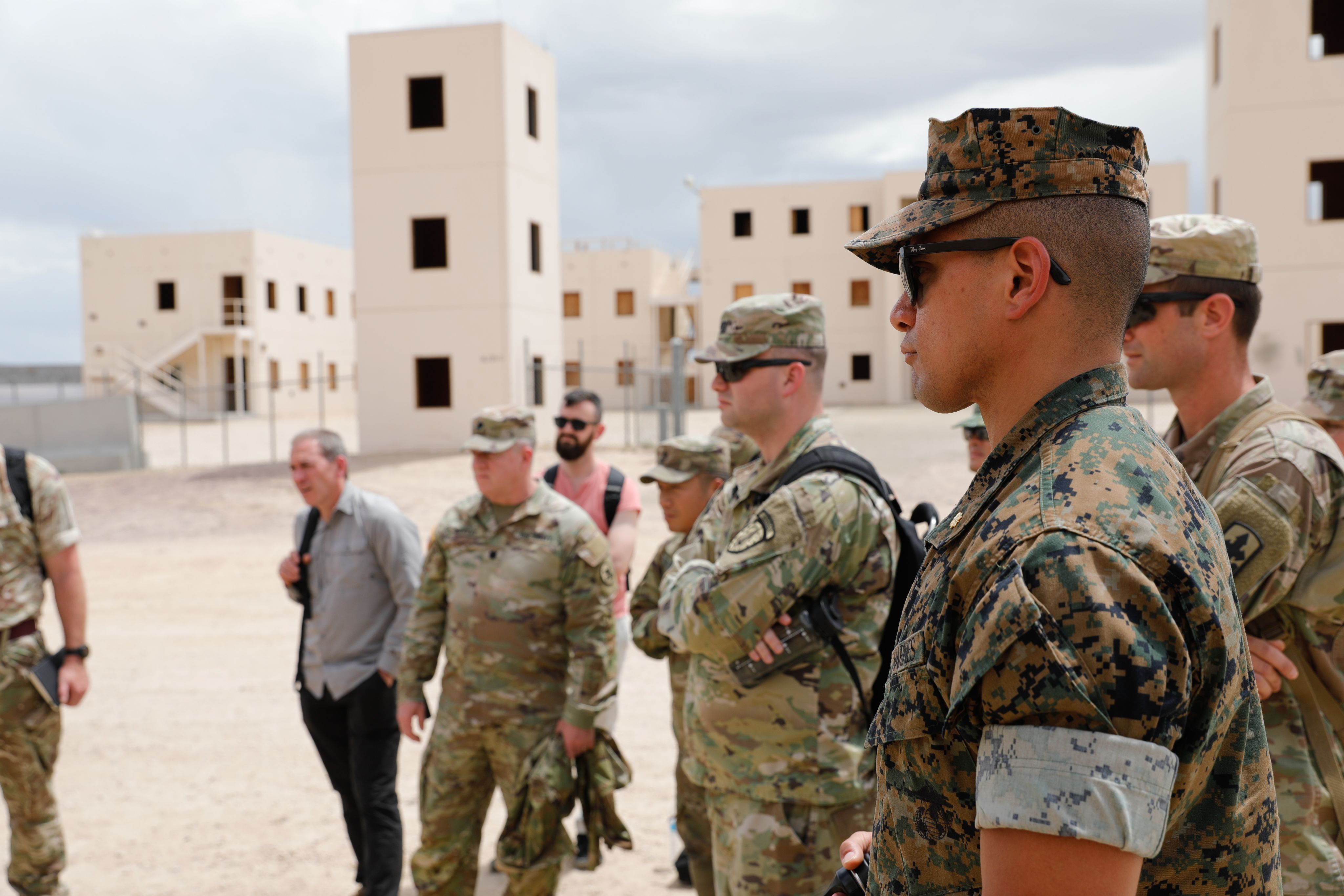 Marine, Soldiers and civilians look at container buildings.