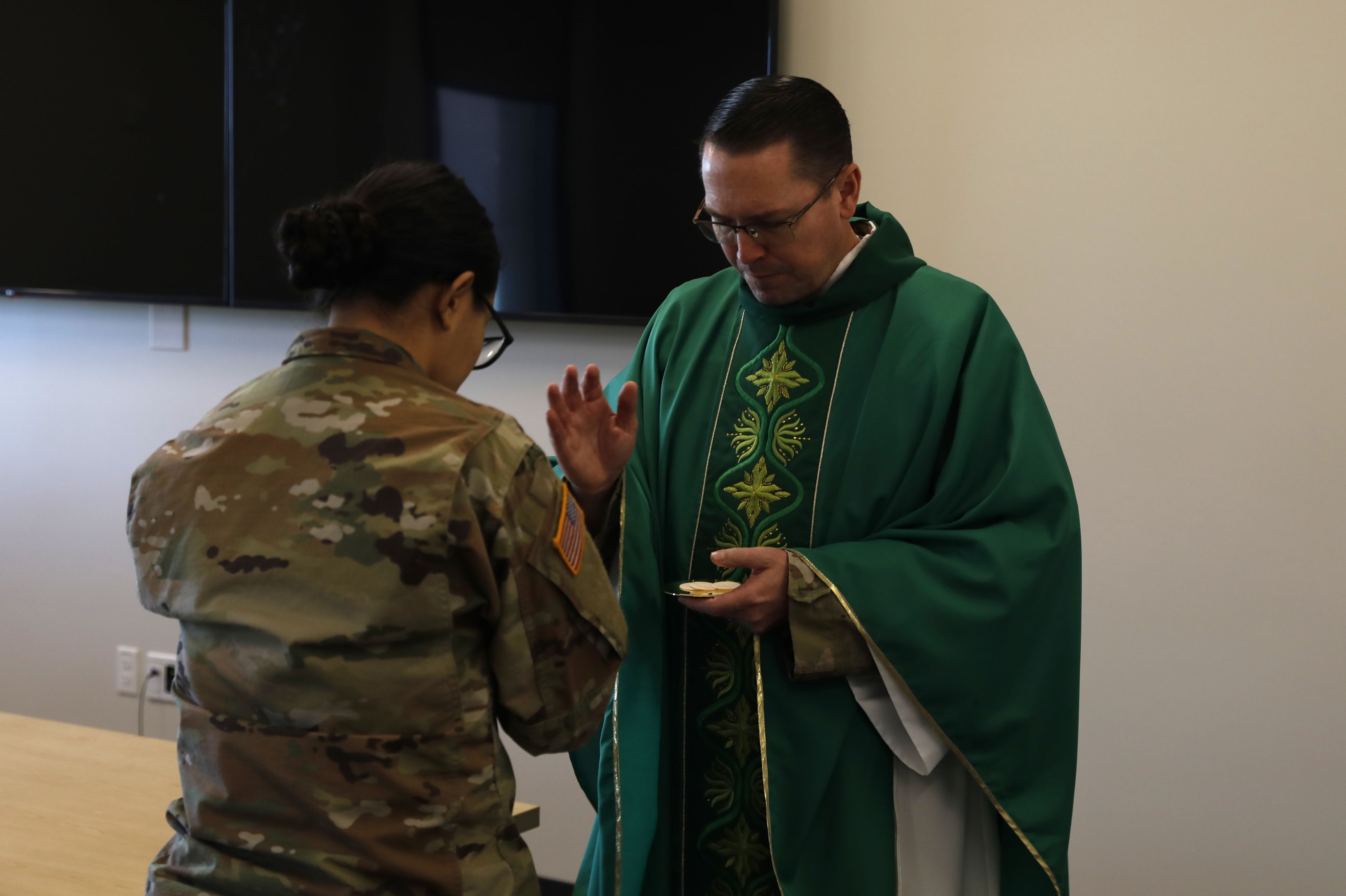 A chaplain (right) offers communion to a Soldier