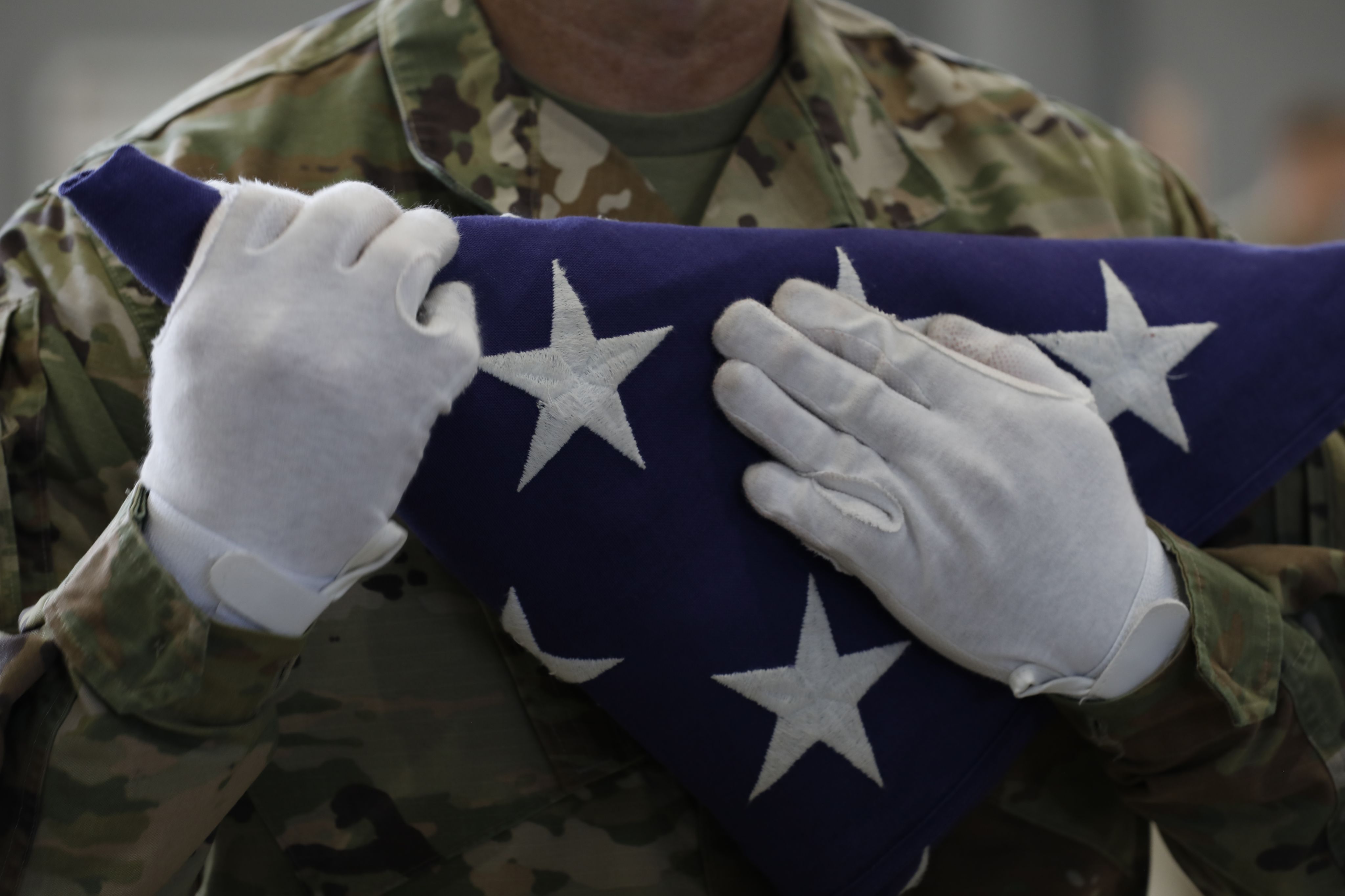 Soldiers holds folded flag to chest