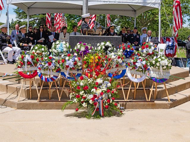Seven large and colorful wreathes are displayed at the front of the speaker's pedestal at Oakhill Memorial Park in San Jose, California.