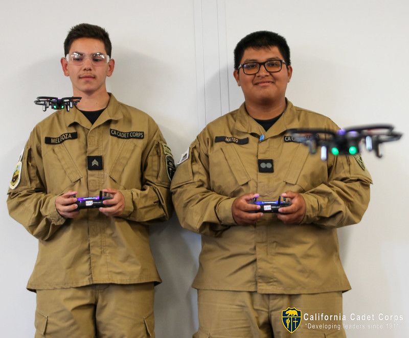 Teenagers at a military-style school pilot small remote controlled quadcopters.