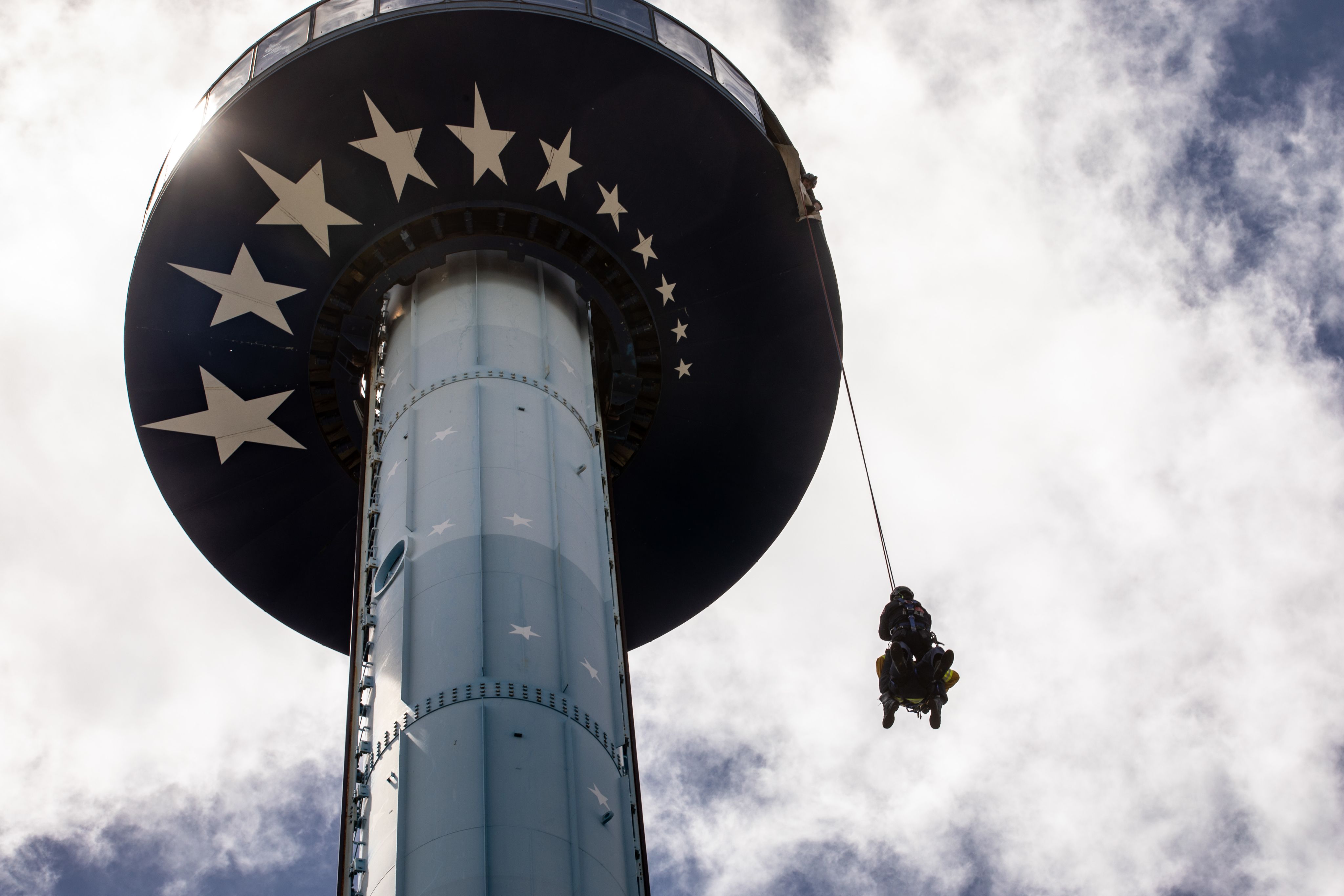 A fire fighter rappels done a tall amusement park attraction