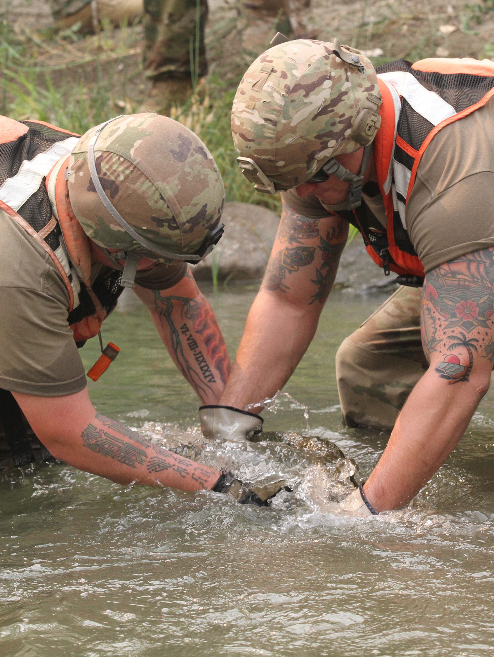 Soldiers move rocks from river to build bridge.
