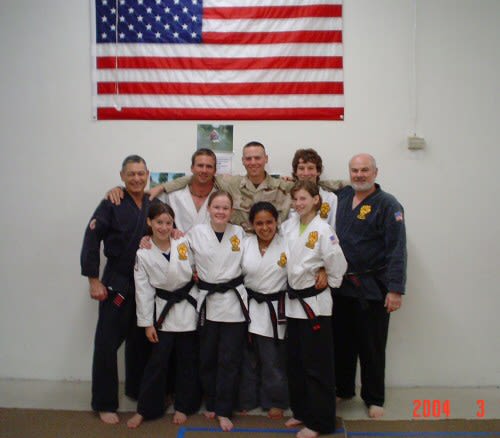 Soldier poses with father and friends in karate uniforms.