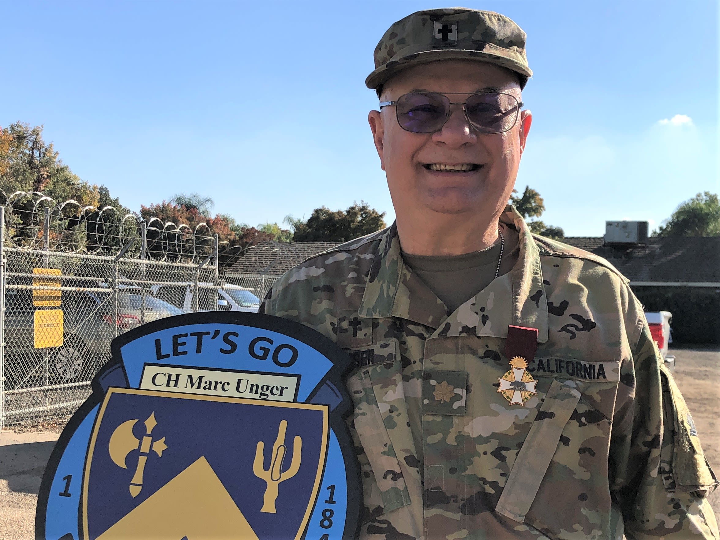 Soldier poses with honorary shield and medal.
