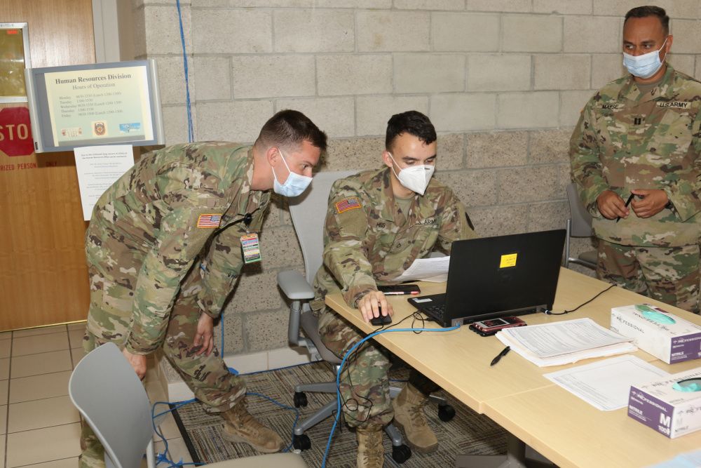 Three Soldiers review information on the screen of a laptop.