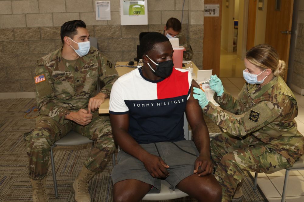Soldier administers a COVID-19 vaccine into the arm of a civilian.