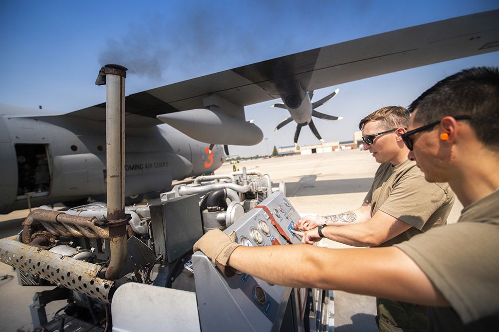 Airmen read gauges attached to airplane.