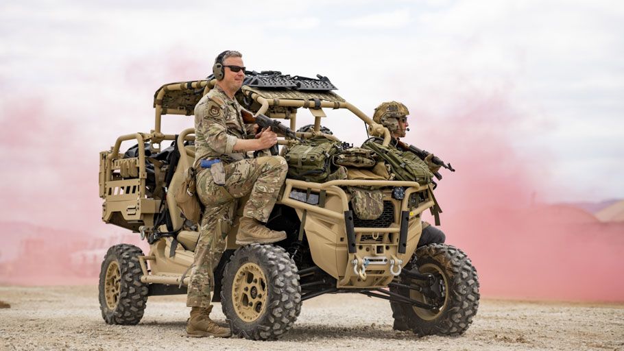 Two Airmen with rifles on a tactical vehicle