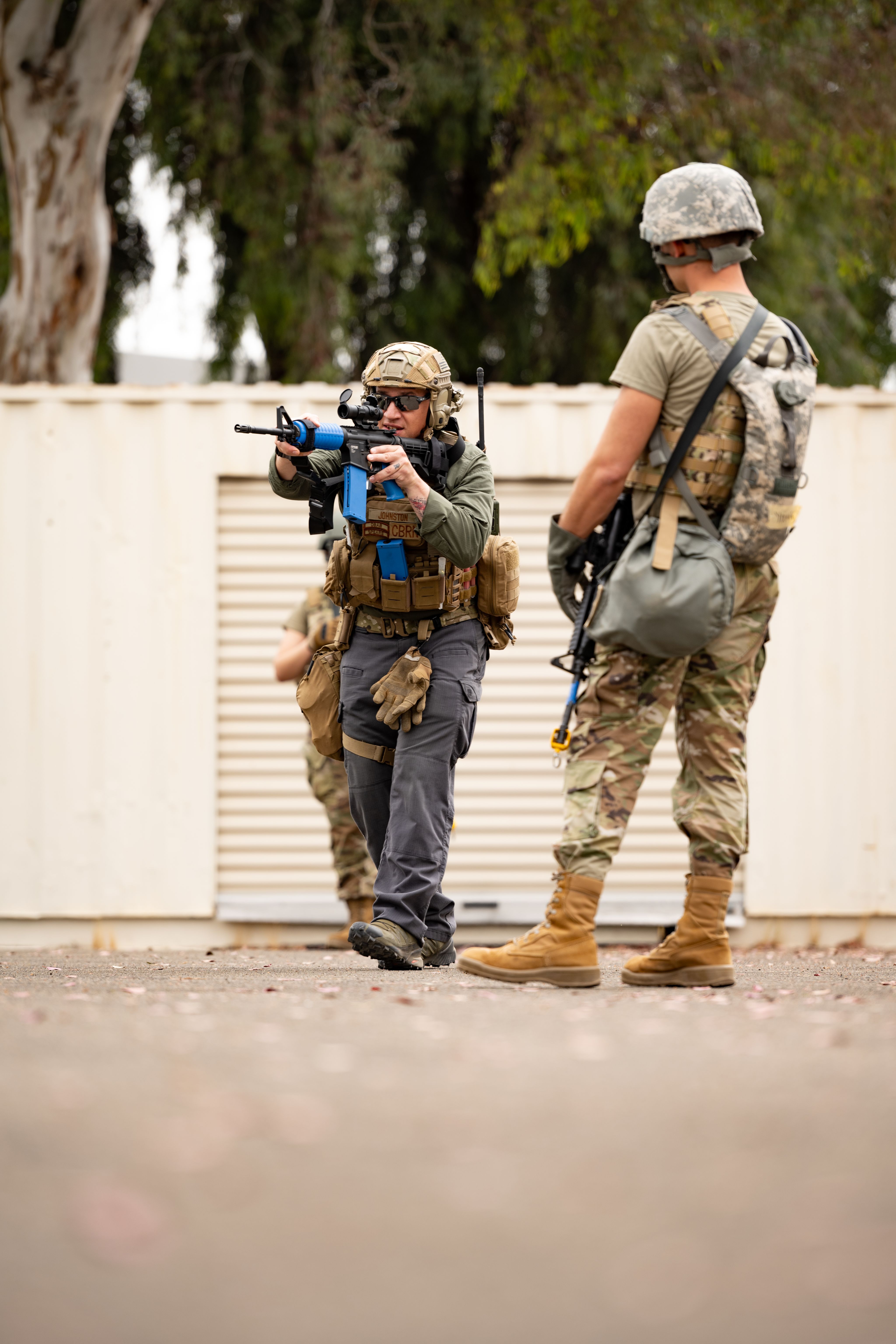 Airman watches another Airman use a rifle