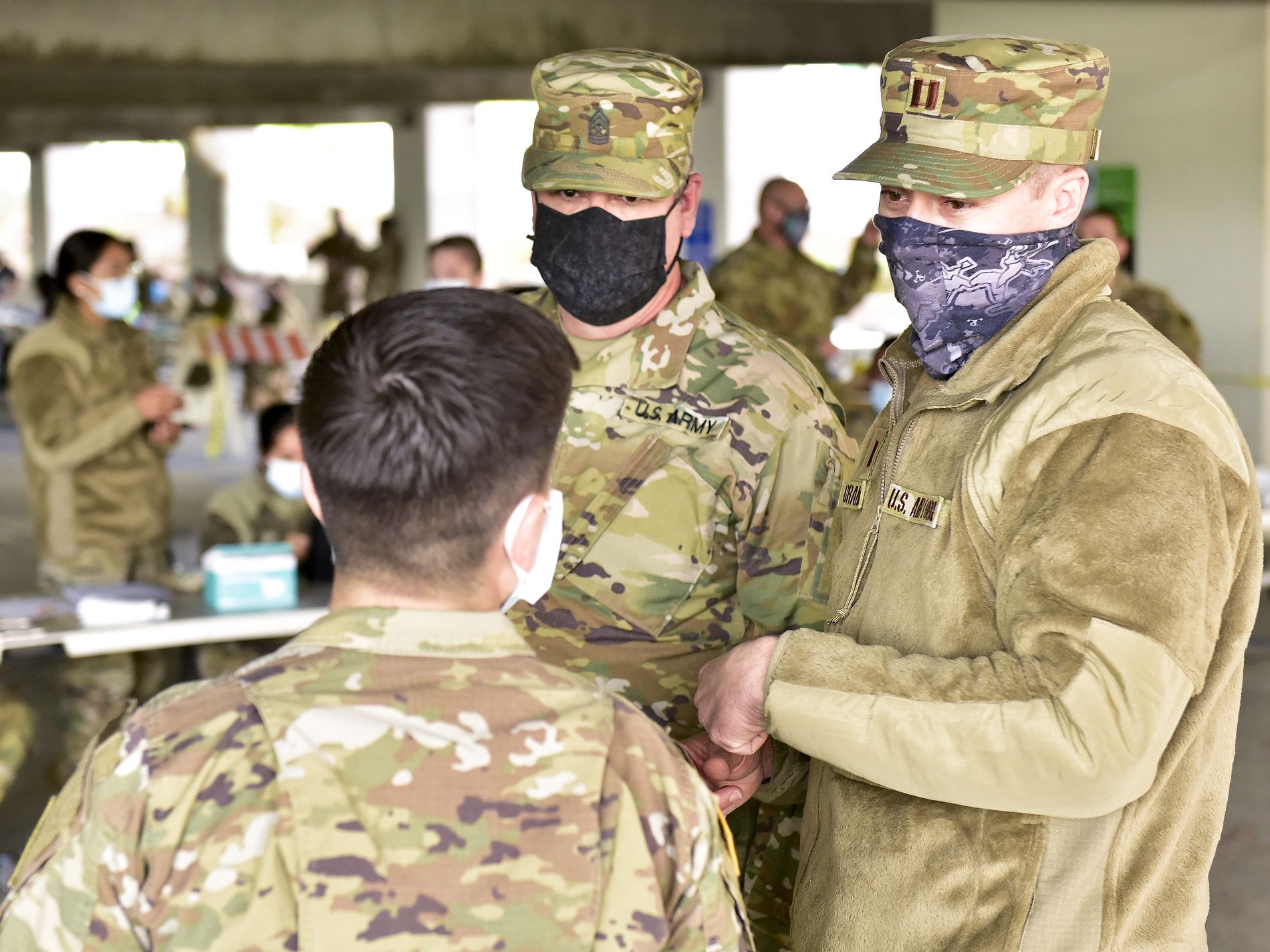 Three service members talk to one another.