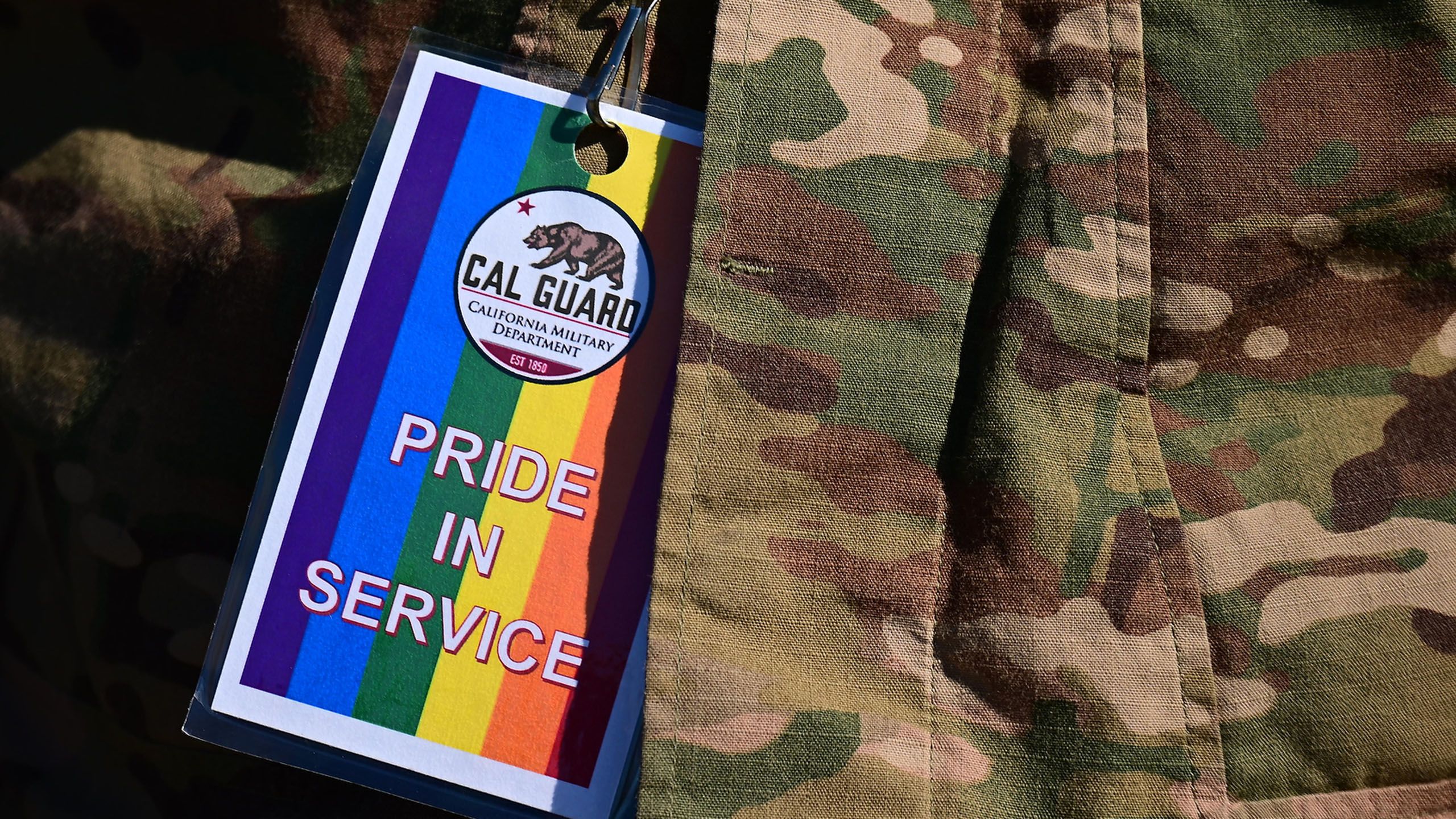 Colorful badge on lanyard reads Pride in Service with Cal Guard logo.