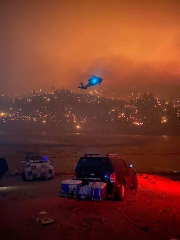 Black Hawk helicopter descends from fire orange sky.