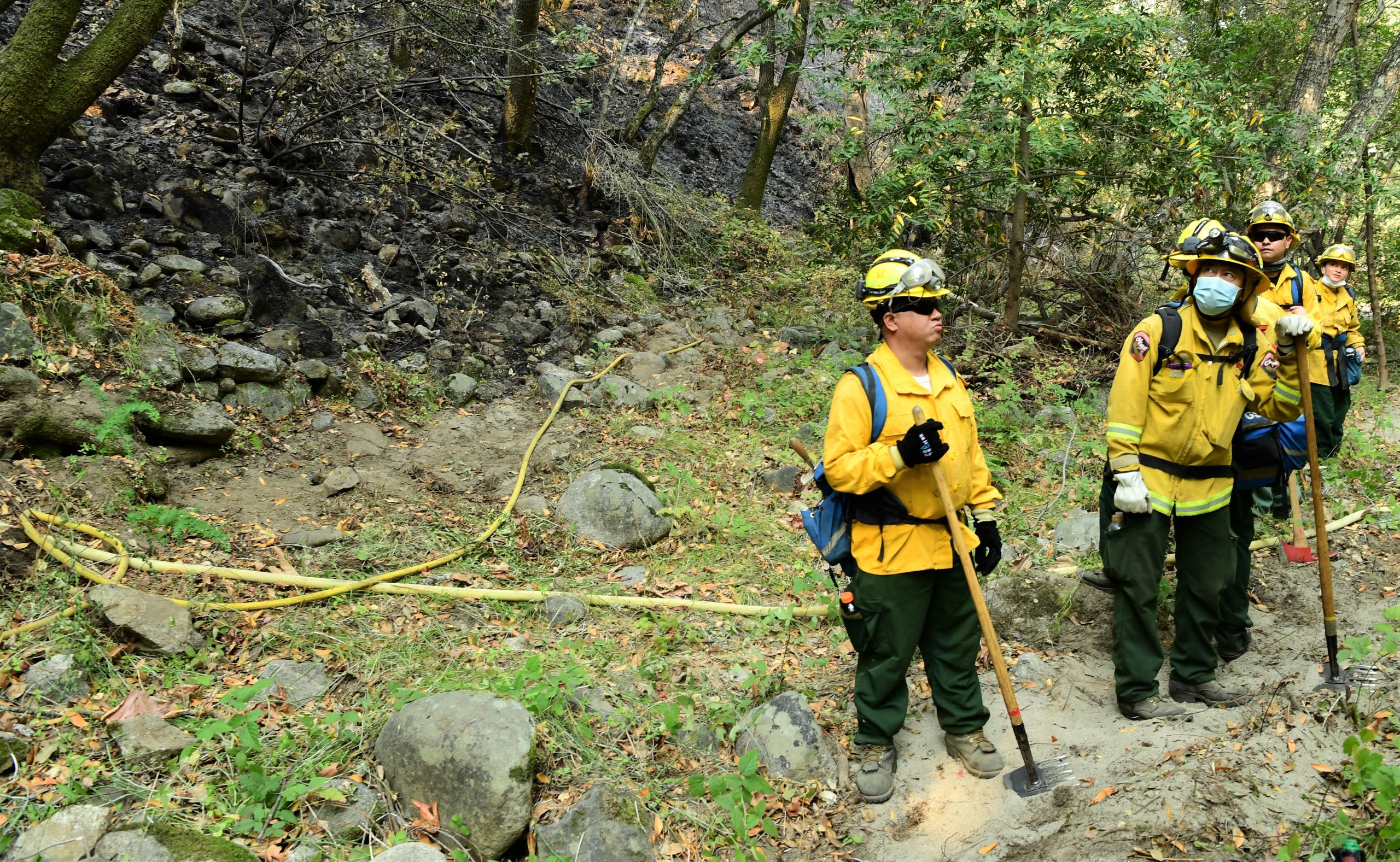 Cal Guardsmen working the fire perimeter of the Carmel Fire study the progress up a steep incline of their team mates.