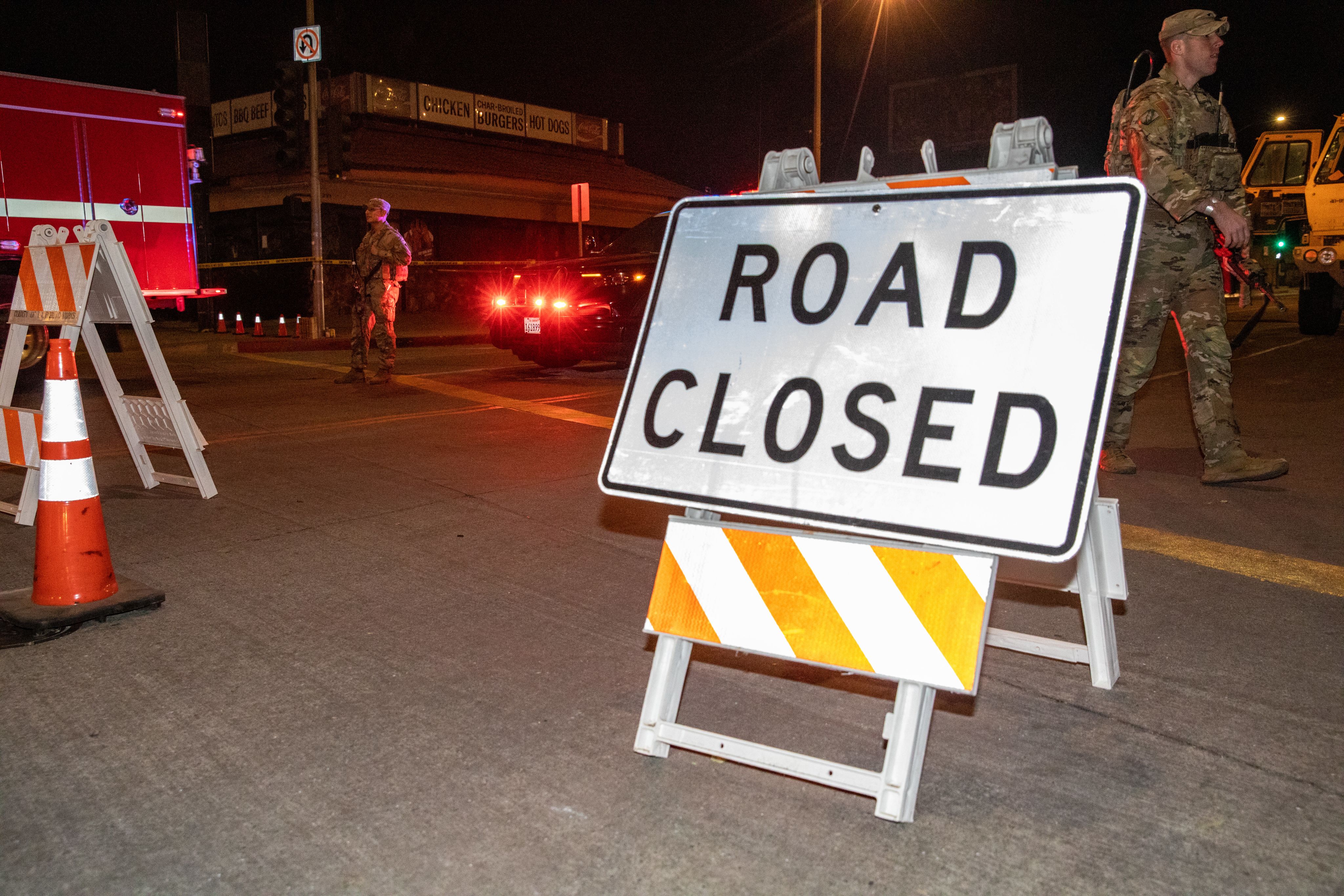 A road closure sign blocks an intersection while Soldiers walk by.