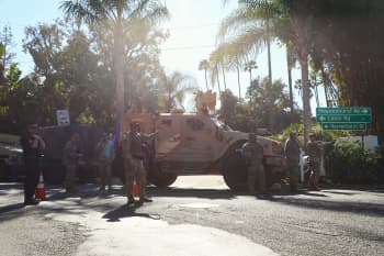 Soldiers stand in front of a humvee at an intersection.