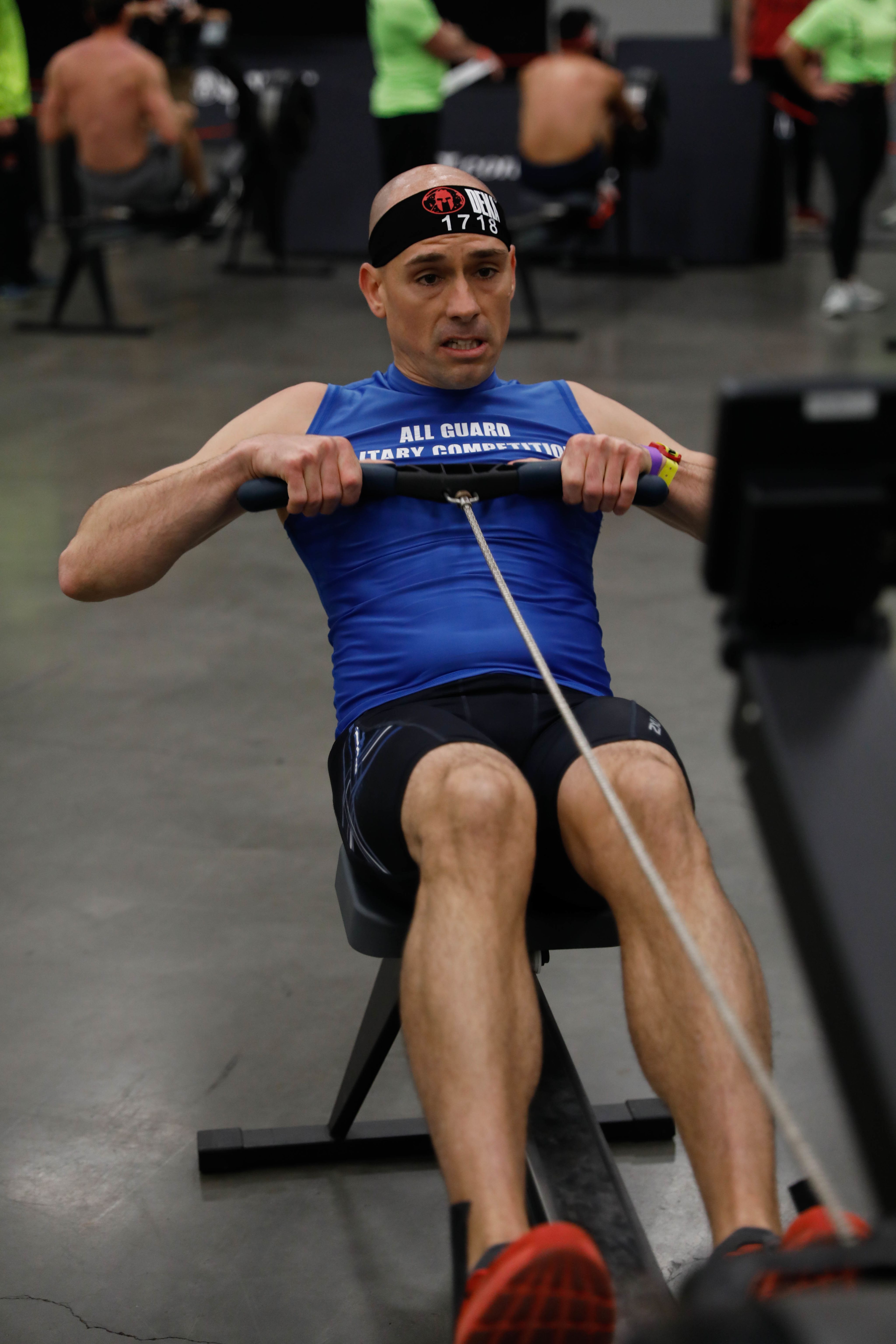 Man in blue tank top uses rowing machine.