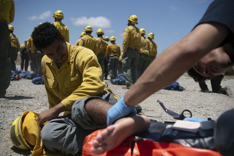 Injured man sits on the ground with his bare foot exposed for treatment