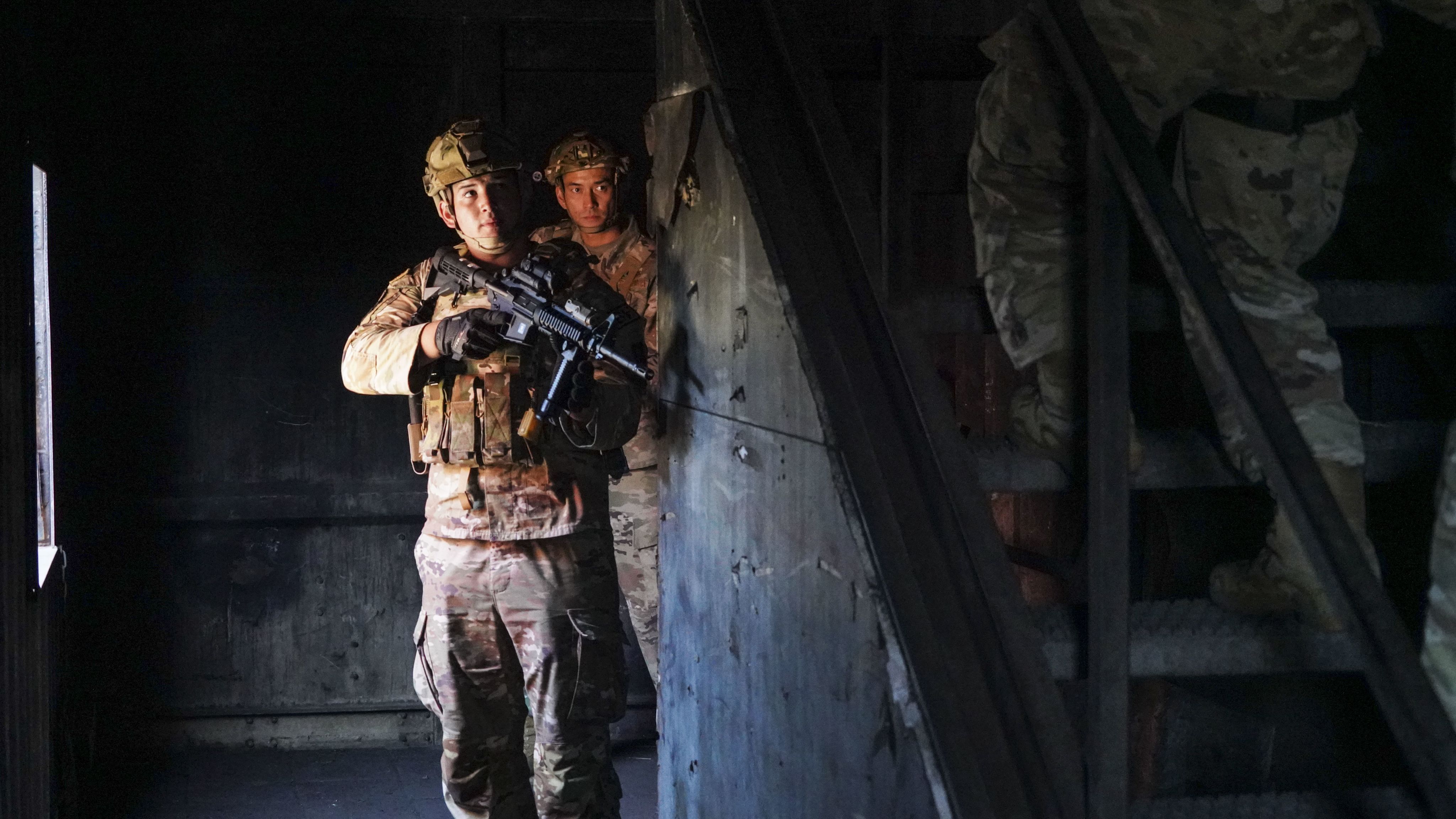 Airman holding weapon climbs stairs.