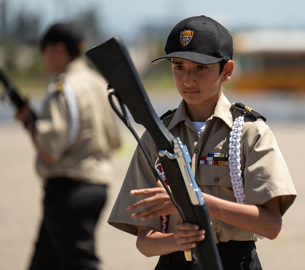 Boy in uniform spins rifle.