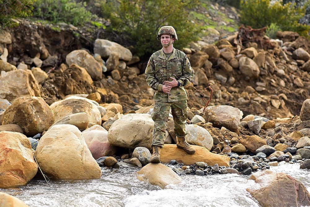 Soldier stands on rocks.