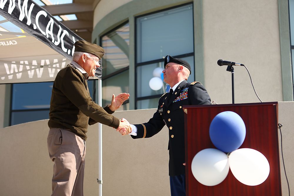 Two men shake hands at podium.
