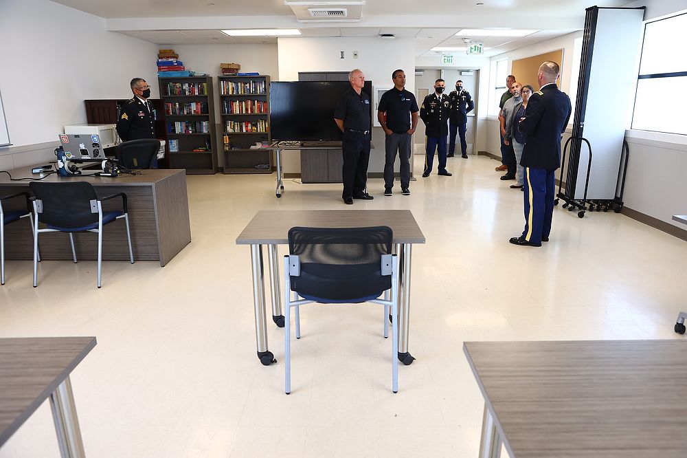 People walk through room with screen and desks.
