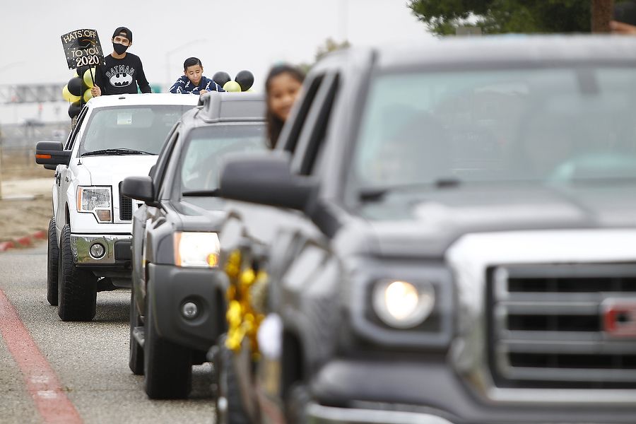 Families and friends in trucks and cars hold up signs celebrating class of 2020