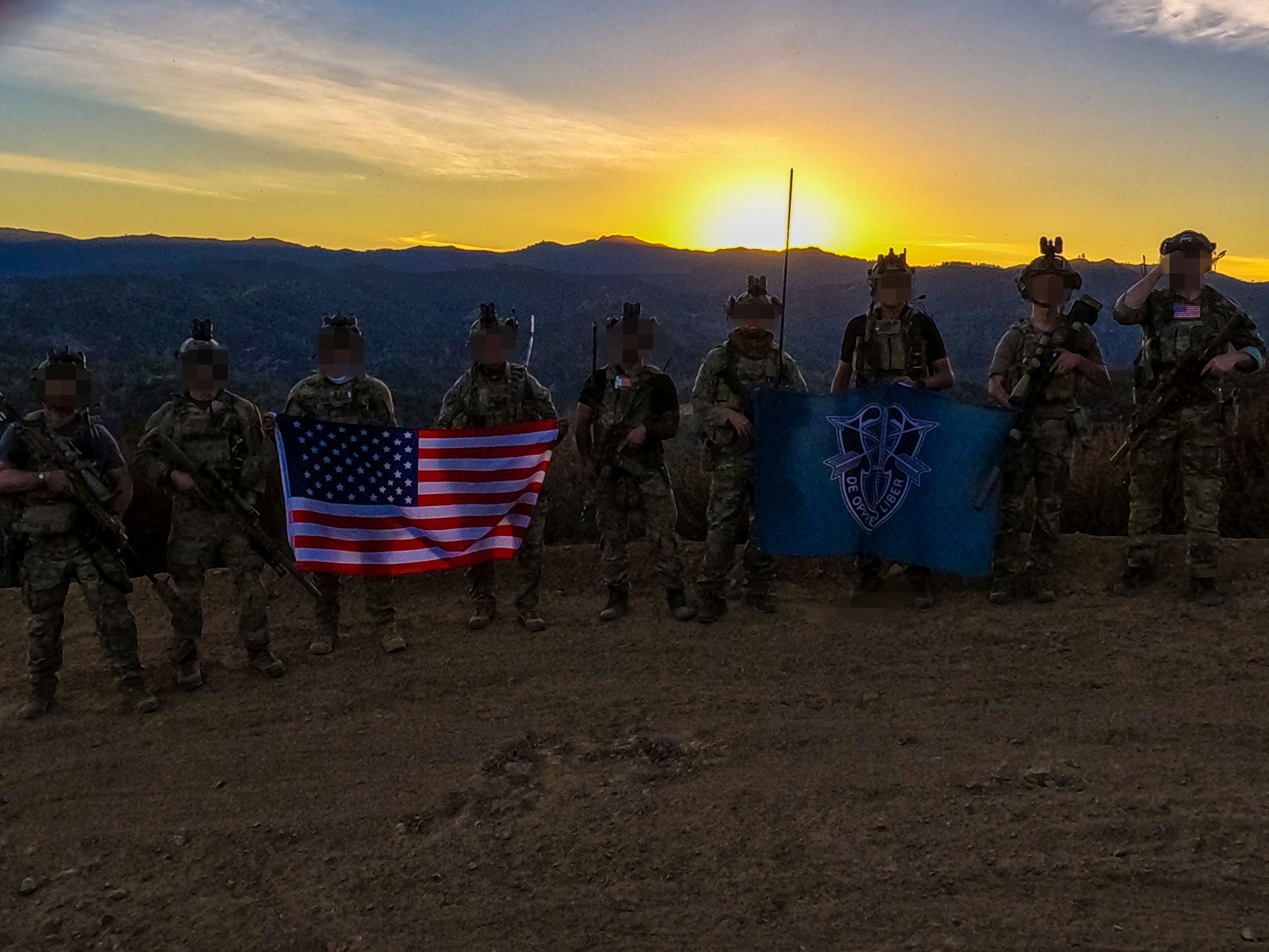 Special Forces Soldiers pose for a group photo with American Flag and Special Forces Flag