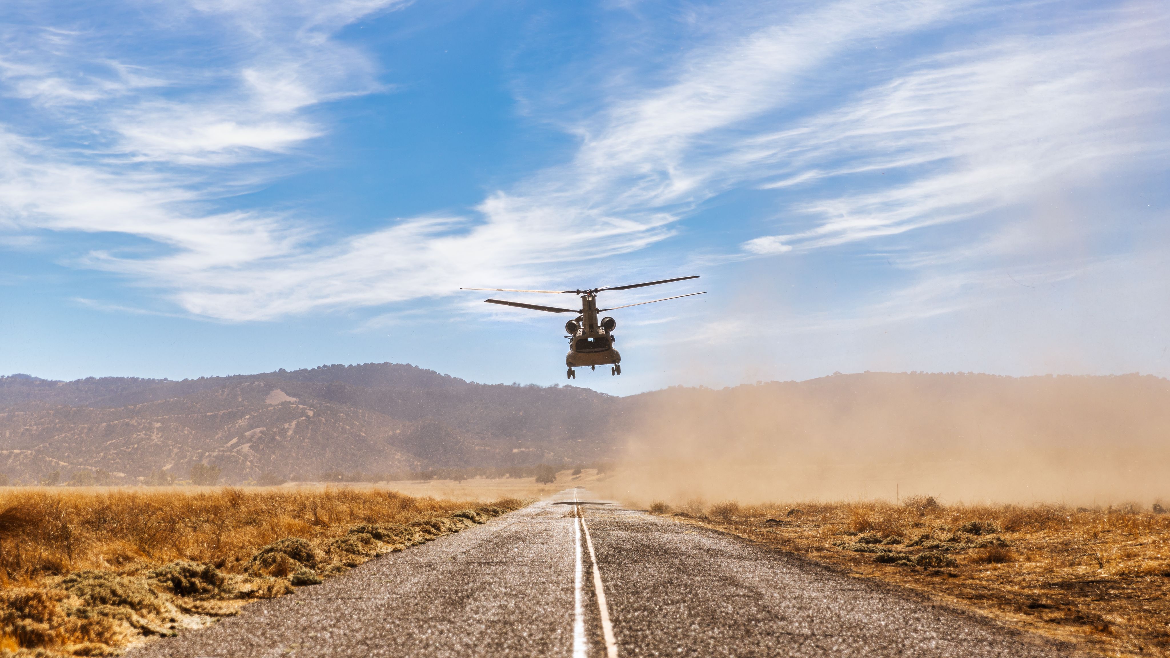 CH-47 Chinook helicopter takes off in front of mountain terrain