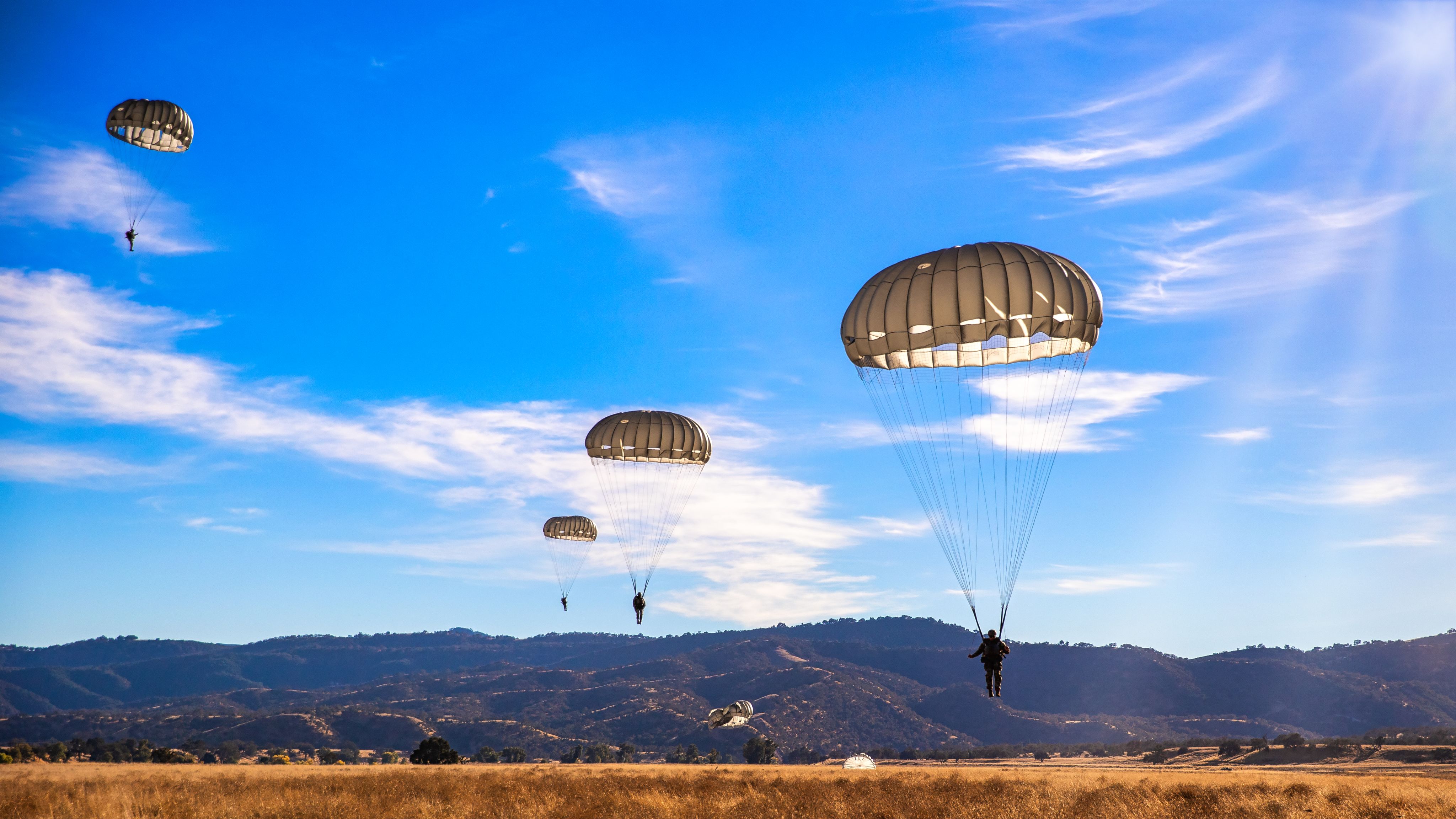 Four Special Forces Soldiers mid-air with parachutes
