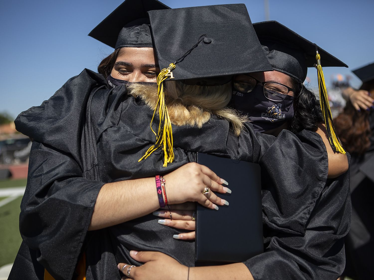 Three graduates hug.