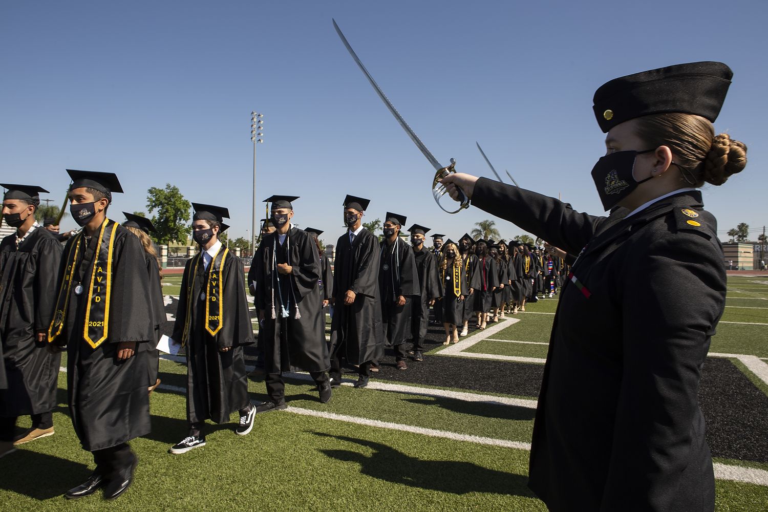 Graduates march under sabres.