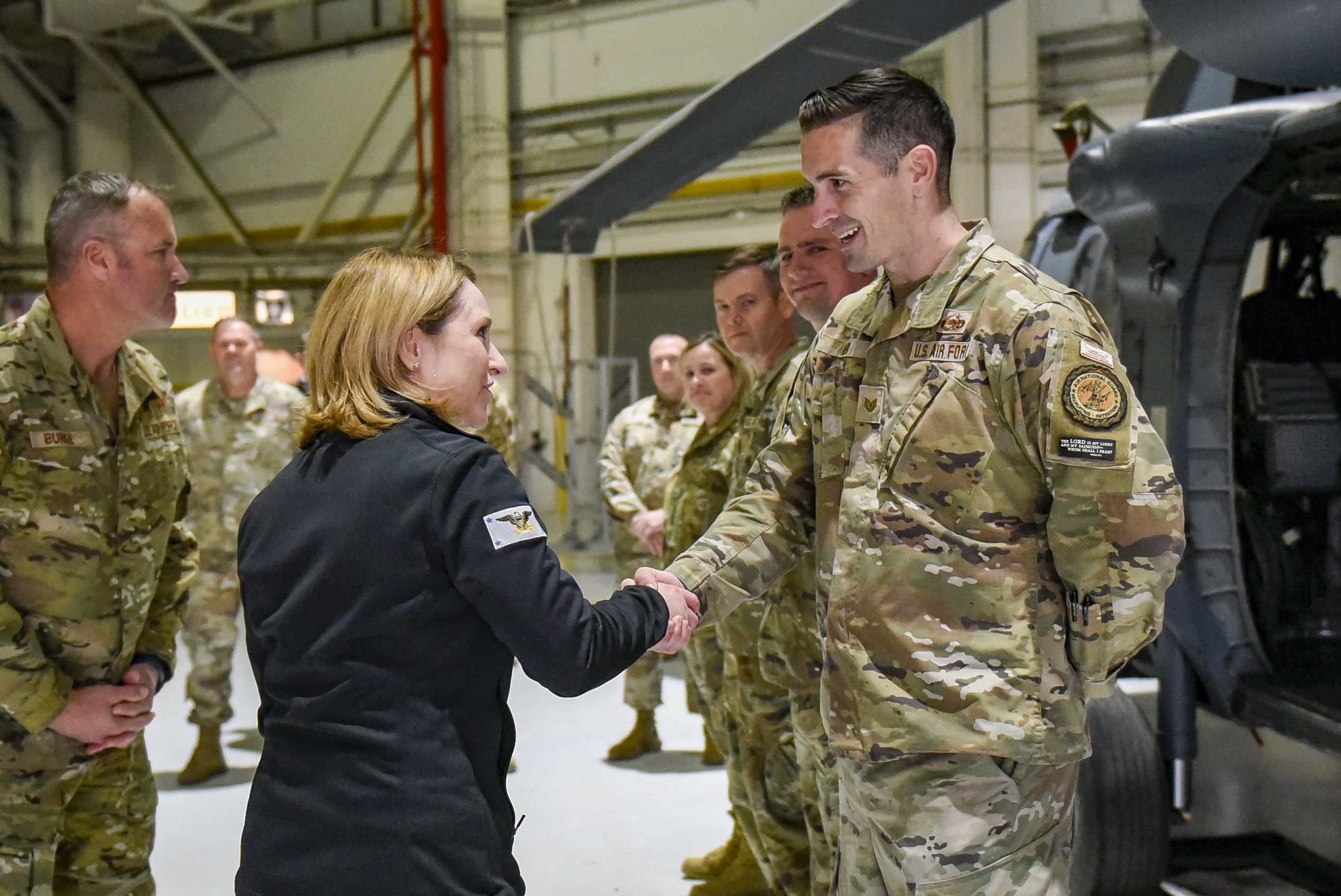 Man in suit presents coin to female Airman.
