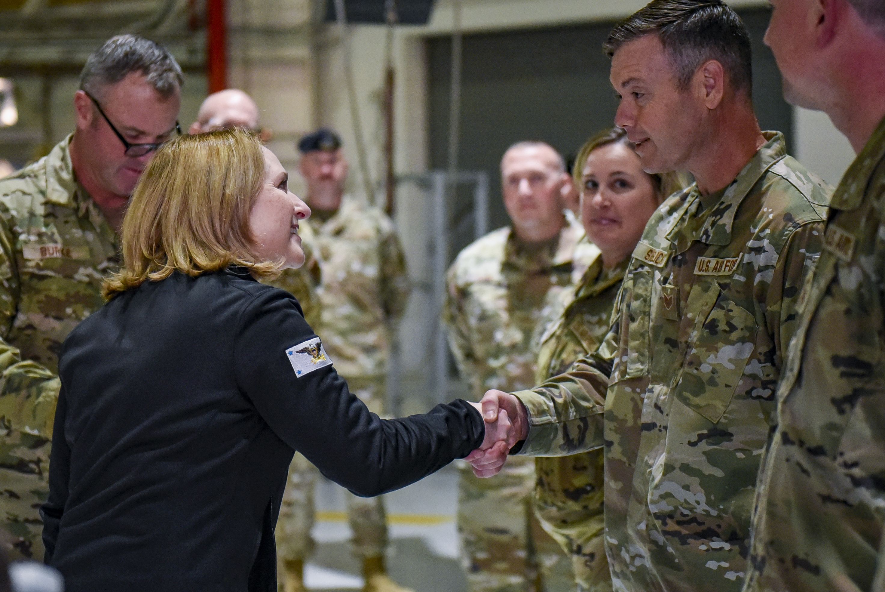 Man presents coin to Airman.