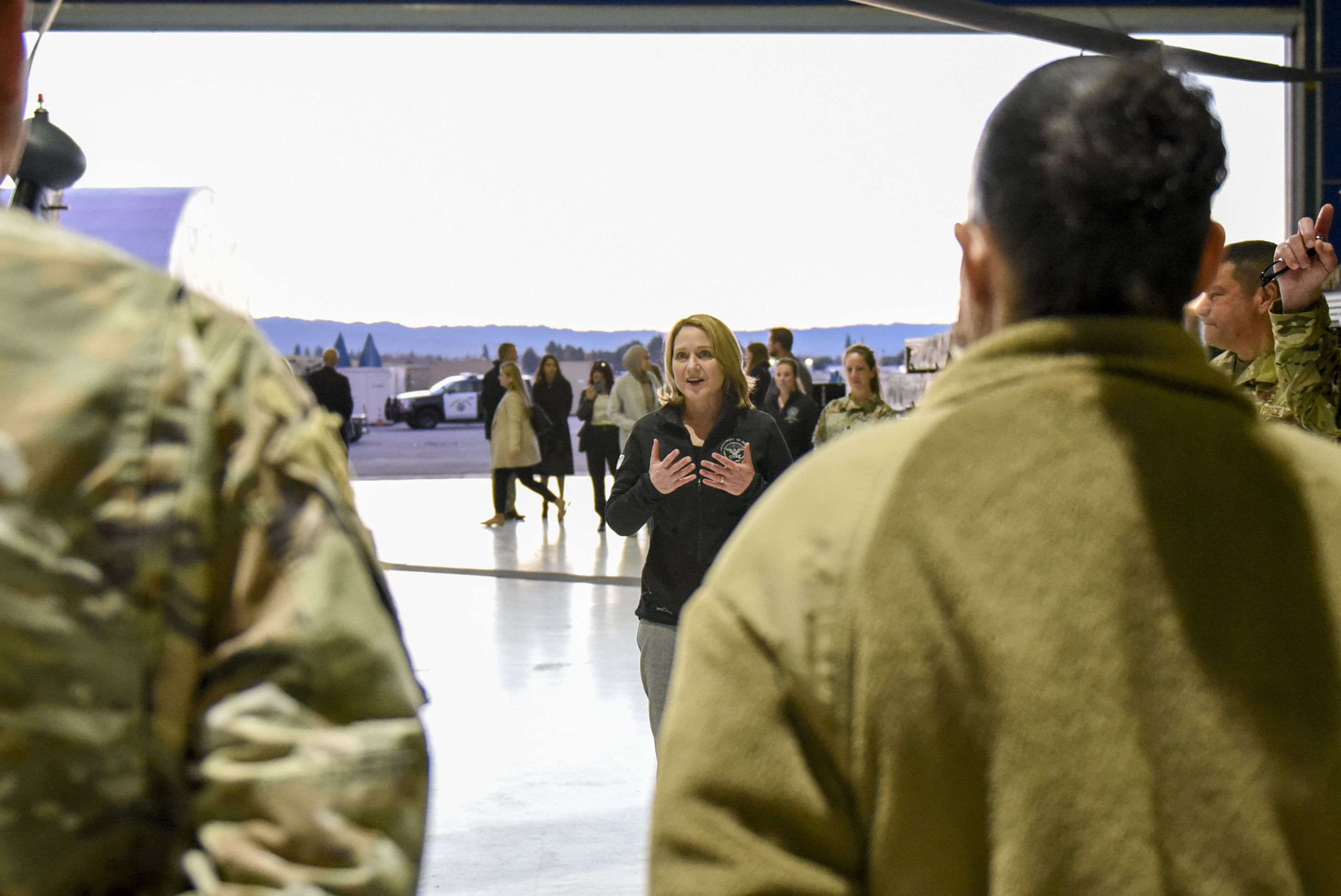 Man in suit talks with military personnel.