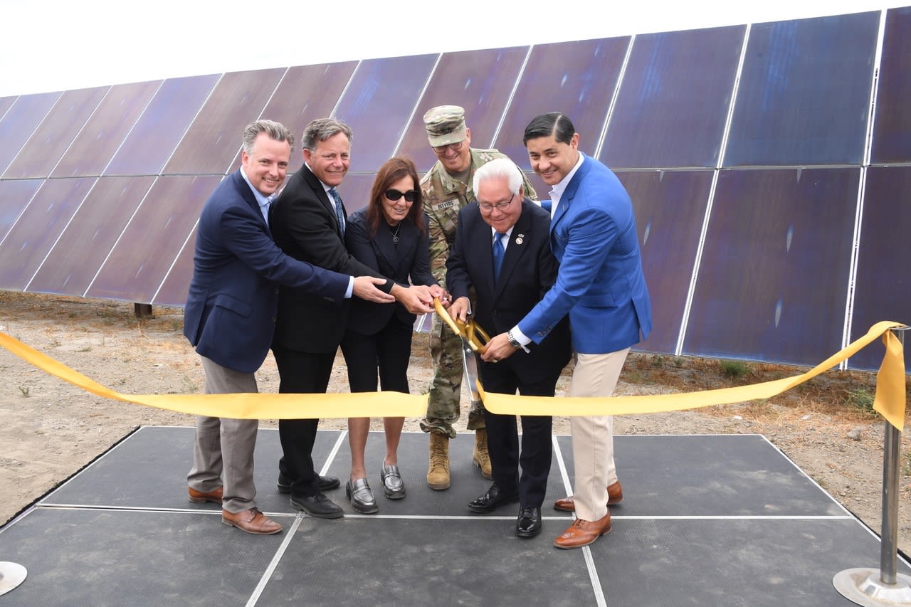 Six people hold scissors to cut a ribbon.